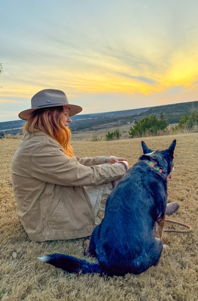 A guest and their dog sit at the Bluff enjoying sunset and golden hour at Contigo Ranch.